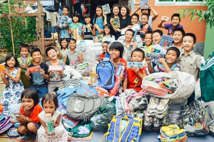 Schoolchildren smiling with donated books and backpacks